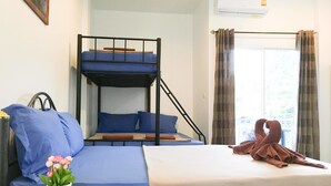 Habitación con literas, escritorio, una mesita con una planta y ventana con cortinas.