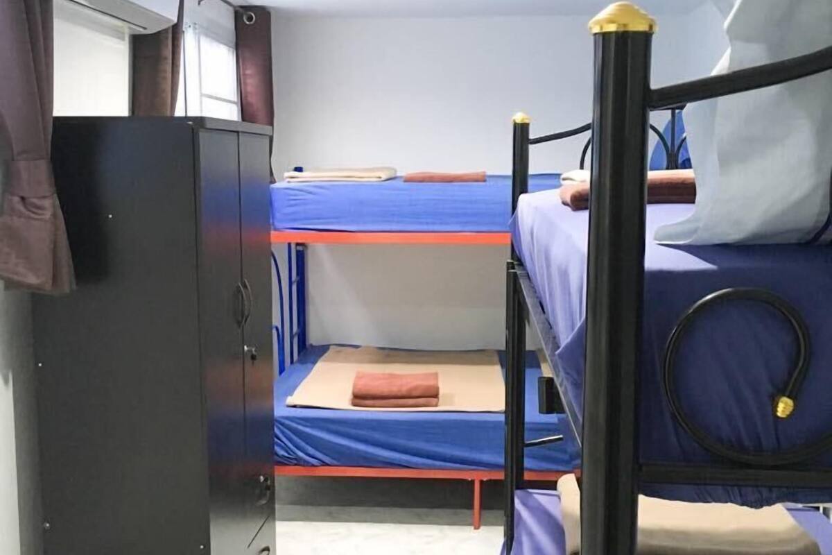 A dormitory room with bunk beds, a wardrobe, and a desk.
