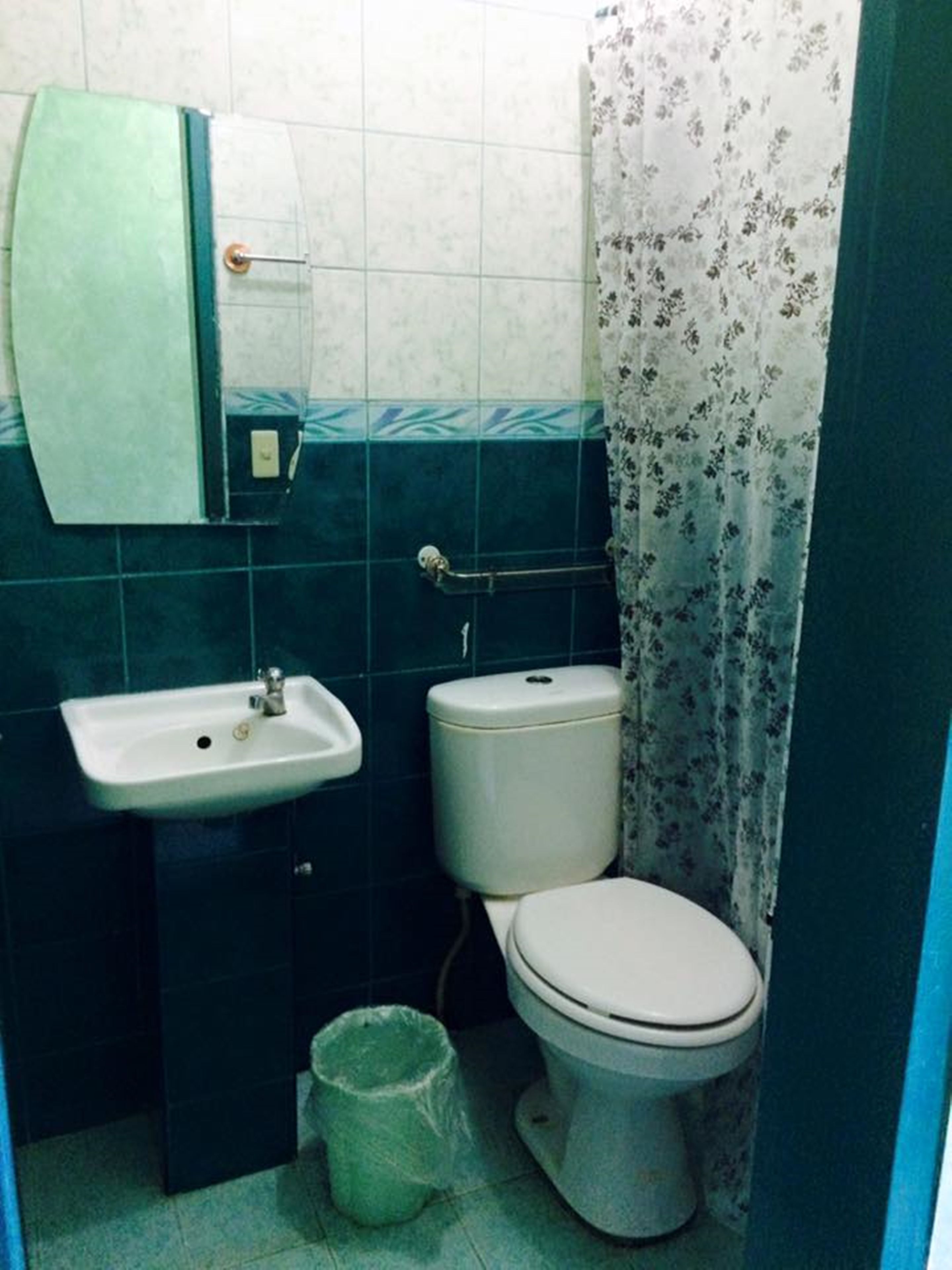 Un baño pequeño con lavamanos, inodoro y un cubo de basura.