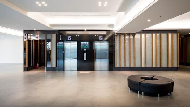 A modern lobby with a reception desk, elevators, and a seating area. - Xianghe Hotel (Mingjian)