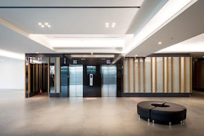 Un lobby moderno con una recepción, ascensores y una zona de estar.