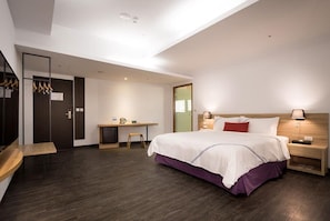 Una habitación de hotel moderna con una cama grande, un escritorio y un pequeño rincón de descanso.