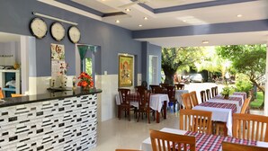 A restaurant with a counter, multiple clocks, and a view of the outdoors. - Areca Resort Cay Cau (Mui Ne)