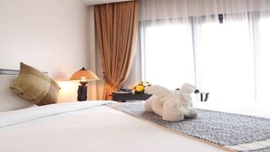 Ein Hotelzimmer mit einem Bett, einer Lampe, einem Nachttisch und einem Fenster mit Vorhängen.