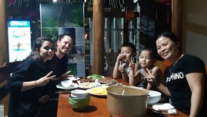 A group of people dining at a restaurant with a variety of dishes on the table, including bowls and plates. - Diep Le Homestay (Phong Nha)