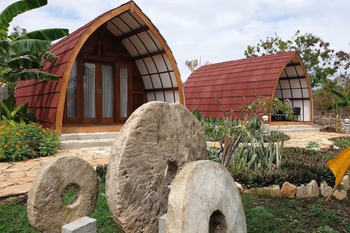 Two modern, arched-roofed buildings with large stone sculptures in the foreground.