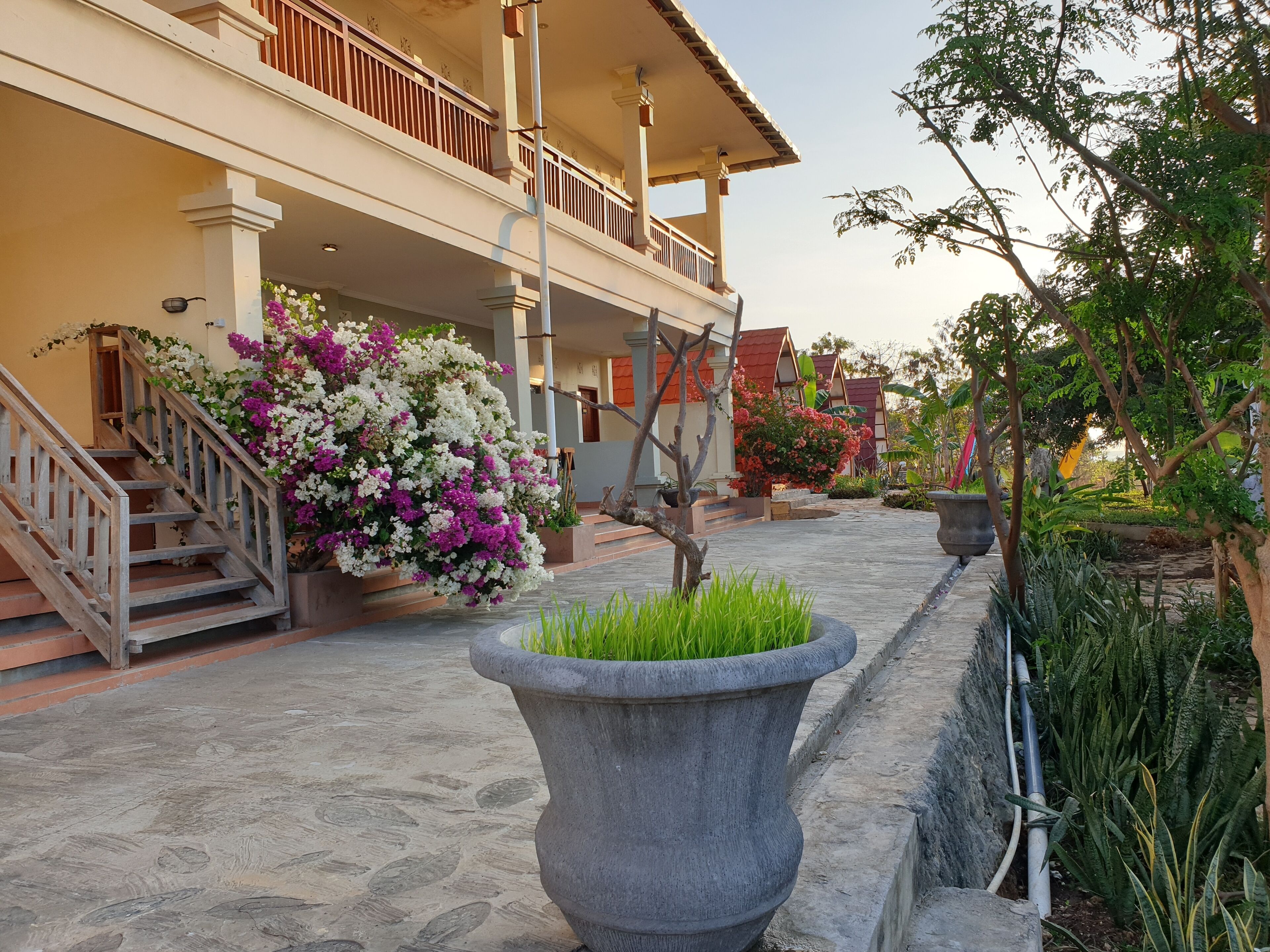 A building with a balcony, a staircase, and a flower bed.