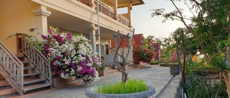 A building with a balcony, a staircase, and a flower bed.