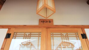 A traditional Japanese entrance with wooden doors and a hanging lantern. - Happy Maru (Jeonju)