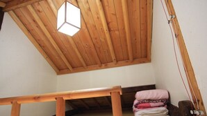 A small, wooden room with a sloped ceiling and a single bed. - Happy Maru (Jeonju)