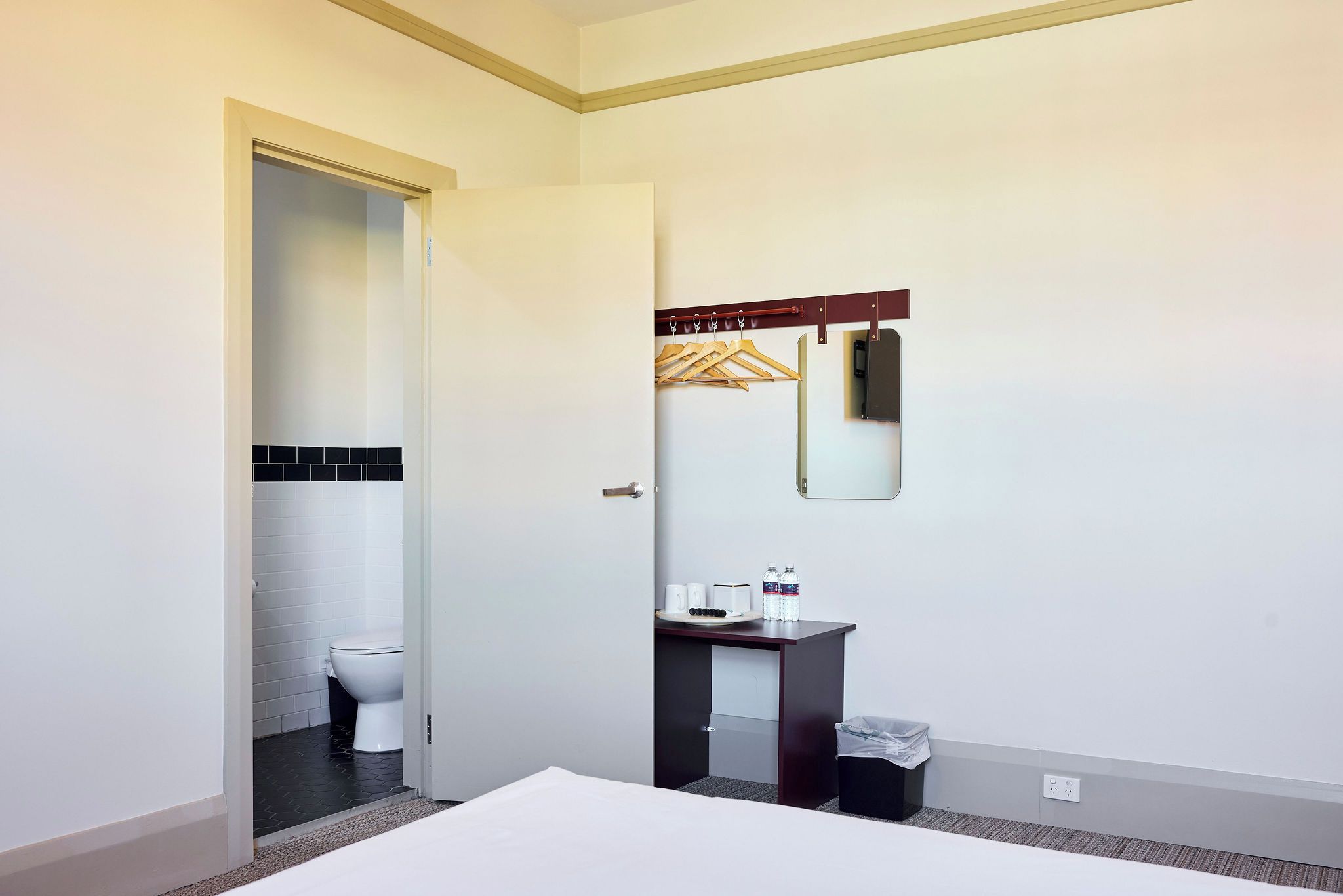 A hotel bathroom with a white toilet, a sink with a mirror, and a towel rack.