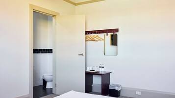 A hotel bathroom with a white toilet, a sink with a mirror, and a towel rack.
