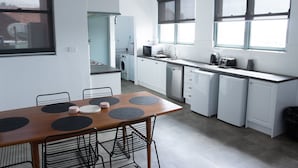 Una cocina moderna con armarios blancos, una mesa de comedor con individuales negros y una ventana con persianas.