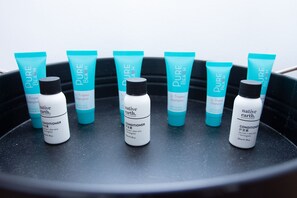 A set of six bottles and tubes of 'Pure Beach' hair care products arranged on a black tray. - Oasis on Beamish Hotel (Campsie)