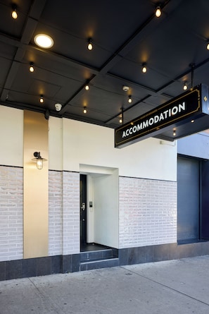 A building entrance with a sign reading 'ACCOMMODATION' and a security camera above the door. - Oasis on Beamish Hotel (Campsie)