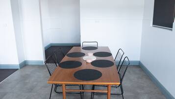 Un salón de conferencias con una mesa de madera, seis tapetes circulares negros y sillas de metal.