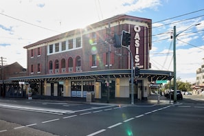 A building with a marquee sign, multiple storefronts, and a street intersection. - Oasis on Beamish Hotel (Campsie)