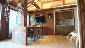 A rustic interior with wooden beams, a dining area with chairs, a TV, and a kitchen area with a sink and cabinets. - Eunhaengro 86.2 (Jeonju)