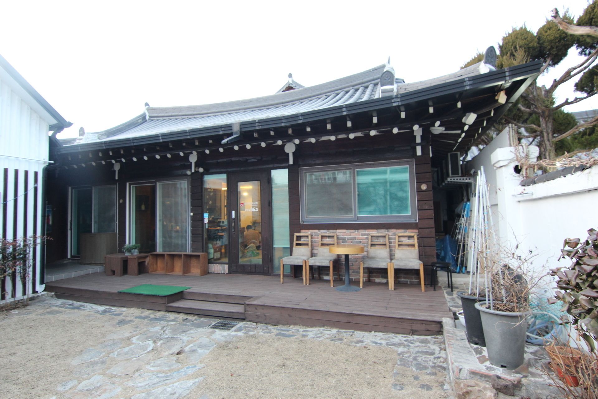 A traditional Japanese-style building with a wooden exterior, large sliding glass doors, and a covered outdoor seating area with benches and a table.