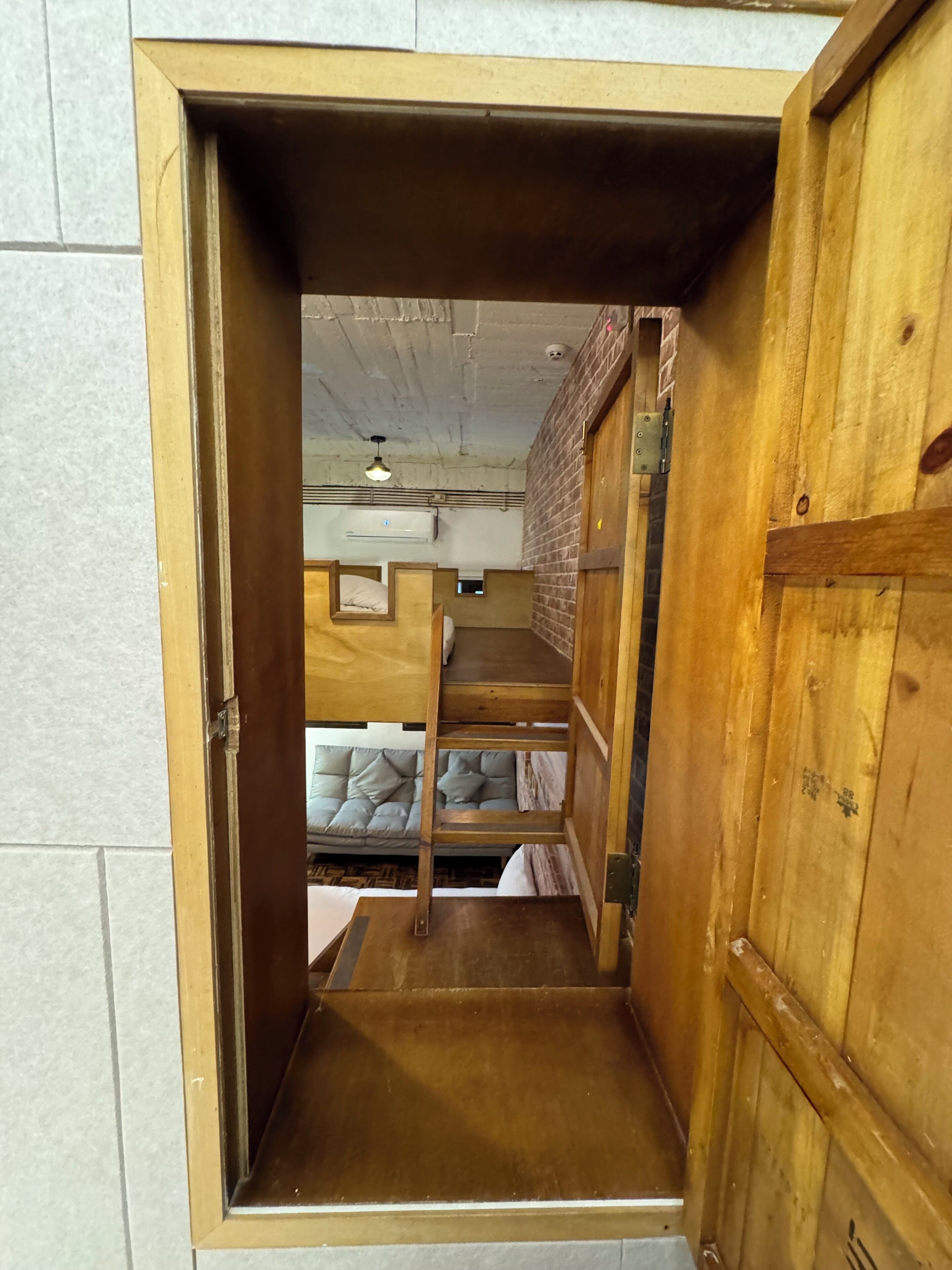 A wooden bunk bed room with a brick wall and an air conditioning unit.