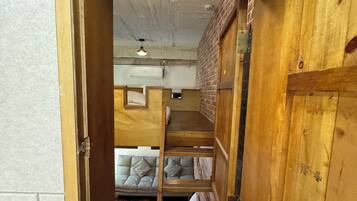 A wooden bunk bed room with a brick wall and an air conditioning unit.