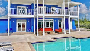 A two-story house with a pool, balconies, and outdoor seating.