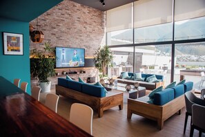 Zona d'estar moderna amb paret de maó, finestres grans i seients confortables.