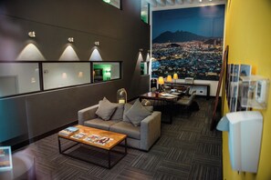 A modern hotel lobby with a sofa, coffee table, and a cityscape view through a large window. - La Silla View Luxury Penthouse Pool and Gym Access (Monterrey)