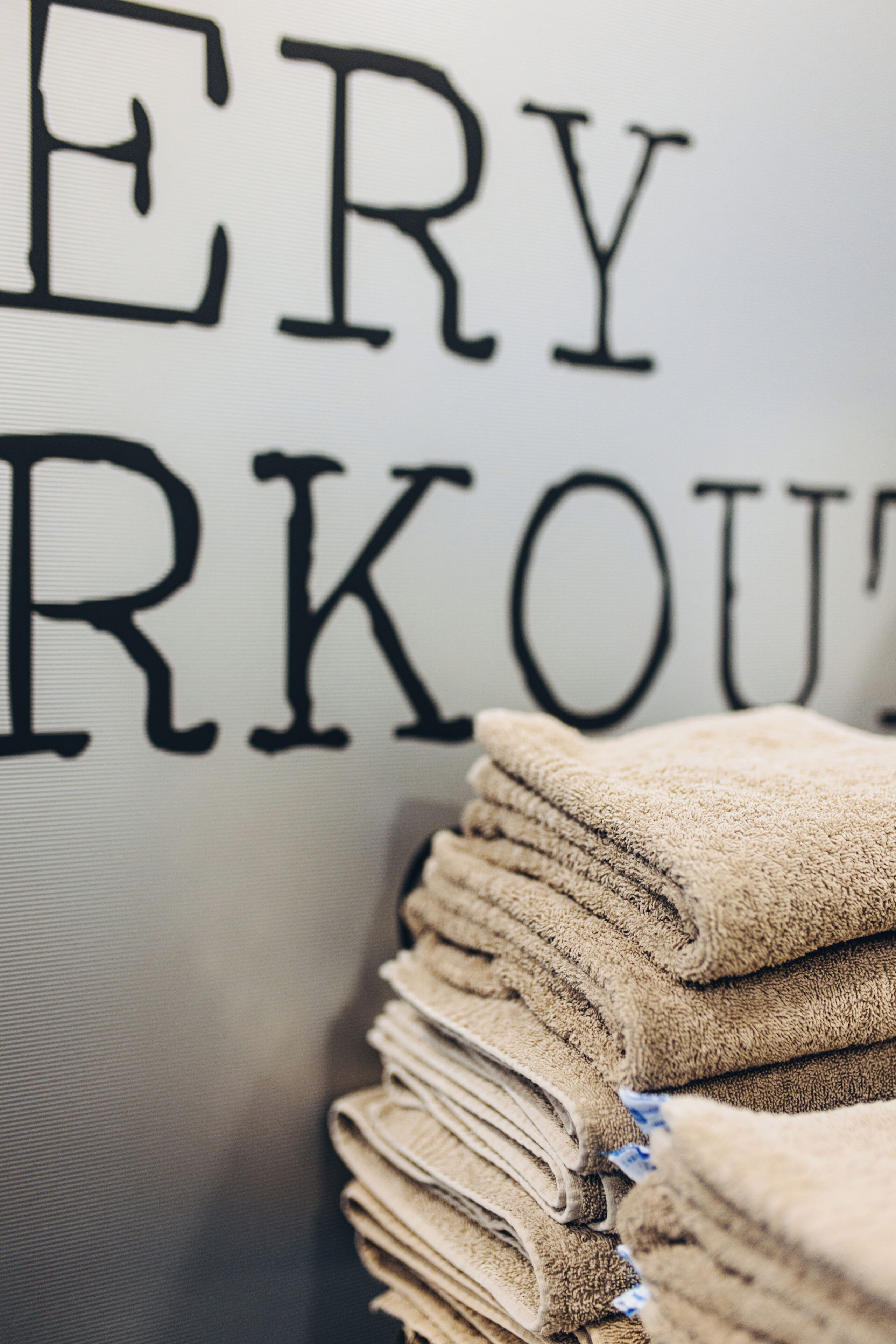 A stack of towels in front of a wall with the text 'ERY RKOUT'.