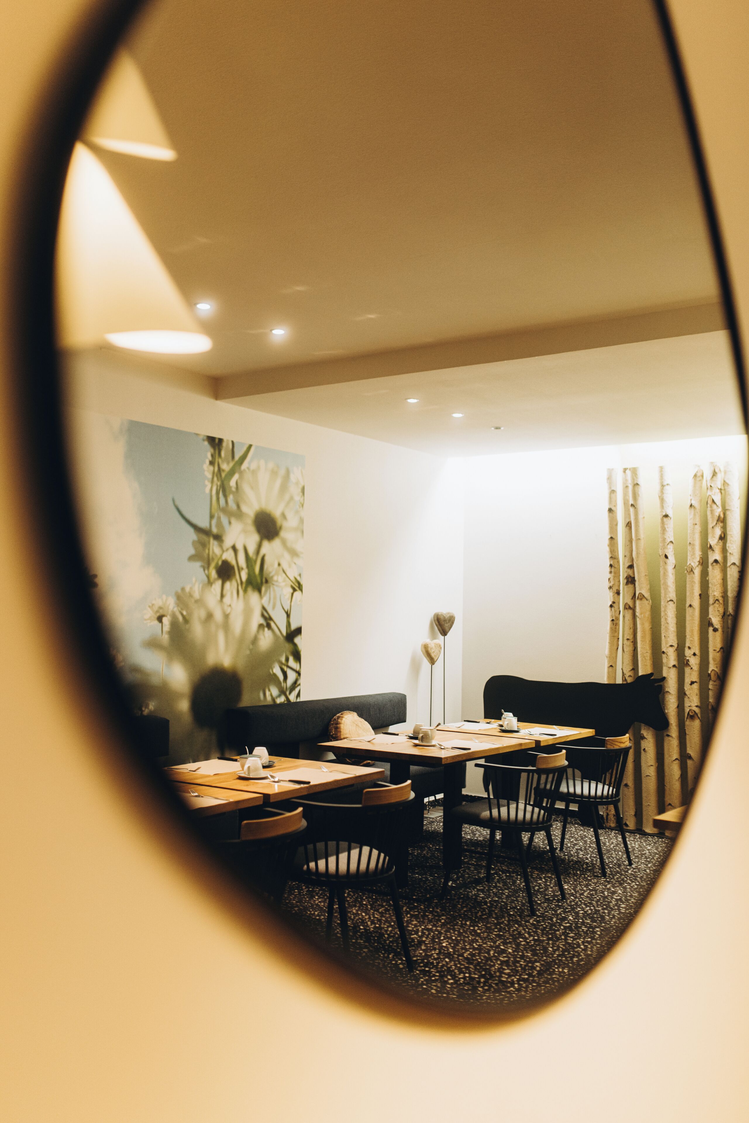 A dining area with a table, chairs, a painting, and a wall-mounted lamp.