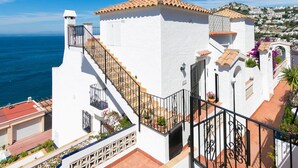 A white building with a tiled roof, a staircase, and a view of the sea. - Lovely apartment in villa for 4 people with WIFI, pool, A/C, TV and terrace (Roses)