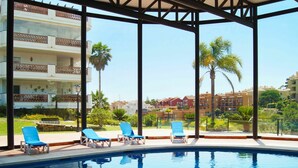 Un área de piscina con sillones reclinables, vistas despejadas de los edificios circundantes y una piscina bien cuidada.