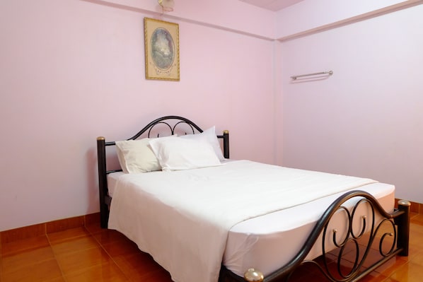 Un lit simple avec un cadre en métal, du linge de lit blanc et une petite table de chevet.