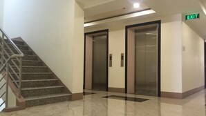 A clean, modern lobby with a marble floor, a staircase with metal railings, and two elevators. - 5F18 Your home baguio (Baguio)