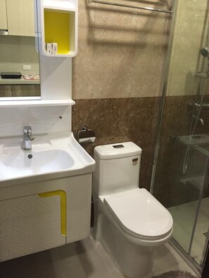 A bathroom with a white sink, a toilet, and a glass shower enclosure.