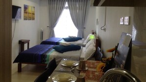 A hotel room with two beds, a dining table with plates and cutlery, a clock on the wall, and a window with curtains. - 5F15 Your home baguio (Baguio)