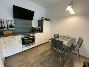 A modern kitchen with a microwave, oven, and a dining table with chairs.