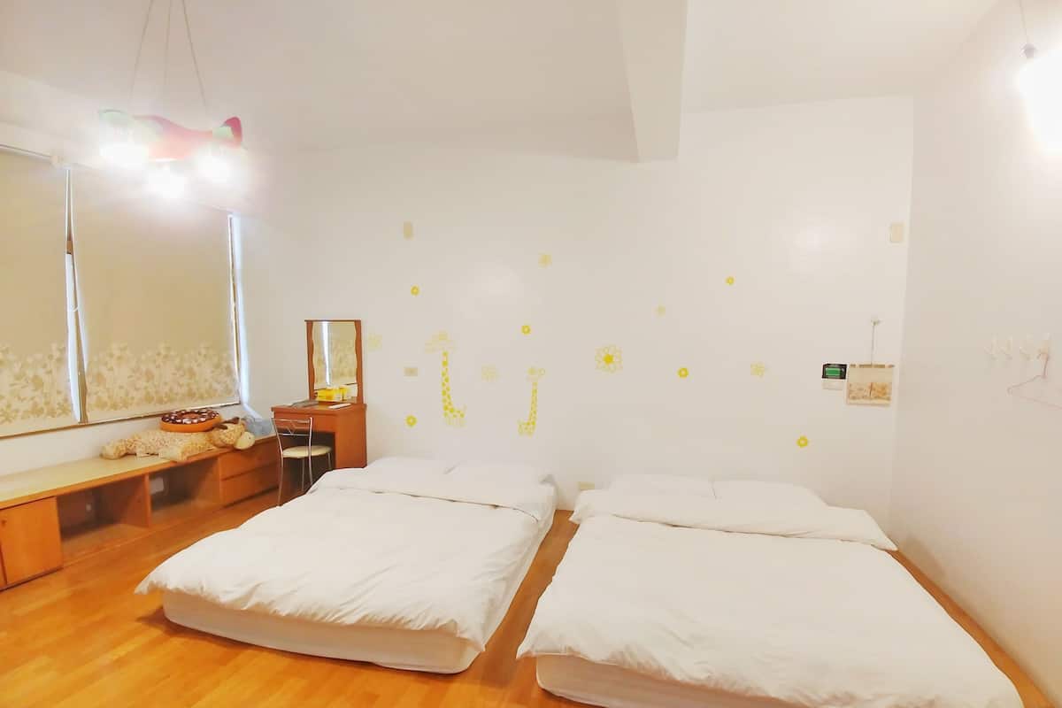 A room with two beds, a wooden desk, a chair, a mirror, and a wall with yellow stickers.