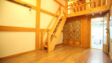Un interior de madera con una escalera, paredes de madera y una puerta tradicional.