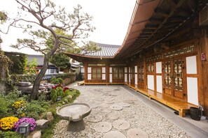 A traditional Japanese courtyard with a wooden building, stone lanterns, and a stone basin. - Samlockhon (Jeonju)