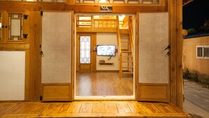 A traditional wooden entrance with a television screen, wooden flooring, and a small shelf. - Samlockhon (Jeonju)