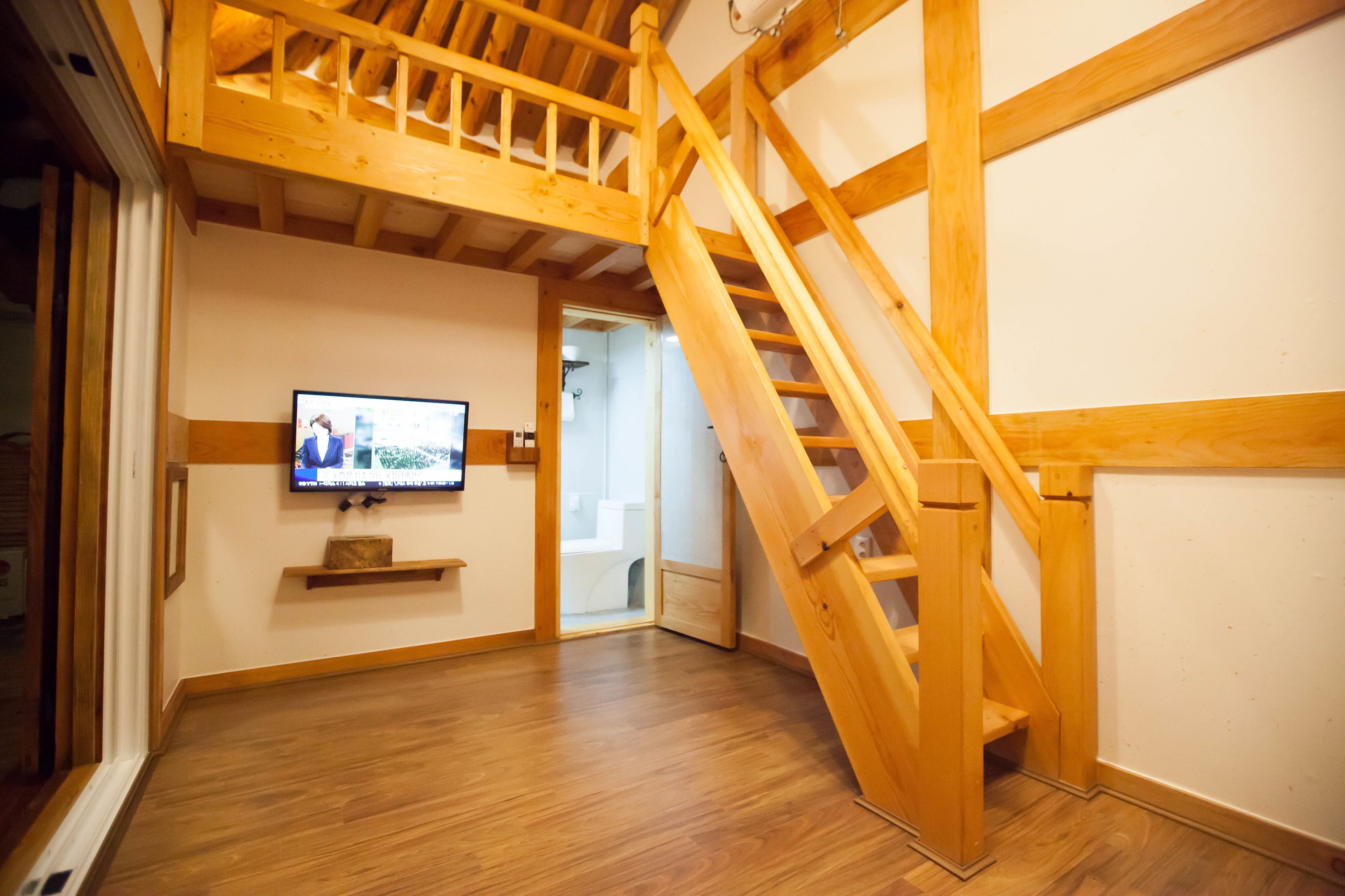 Una escalera de madera en una habitación con un televisor colgado en la pared.