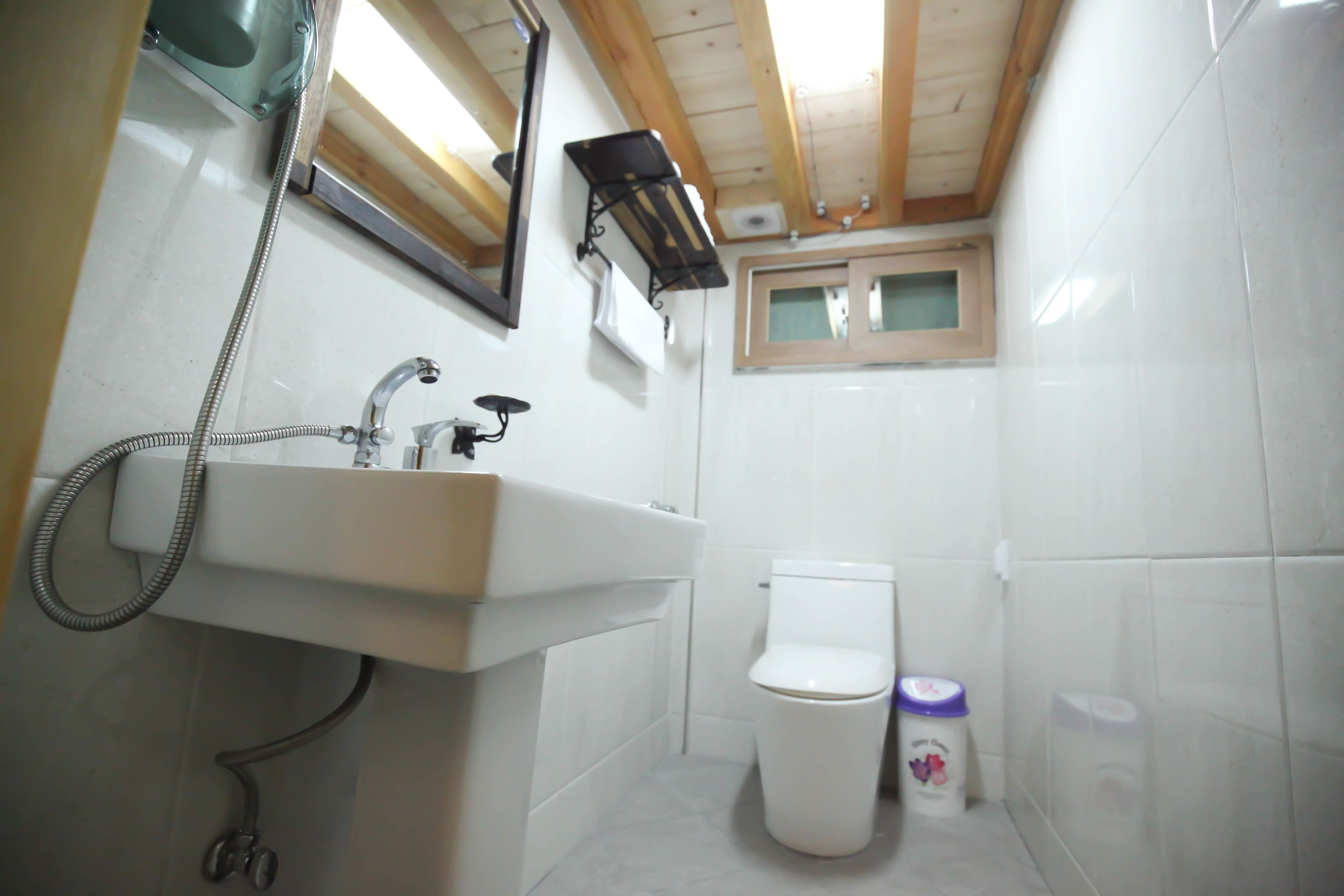 A compact bathroom with a white sink, a toilet, and a shower.