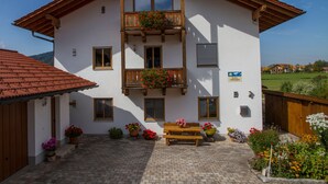 Un edificio de dos pisos con un balcón, contraventanas de madera y un letrero que indica que es una casa de huéspedes.