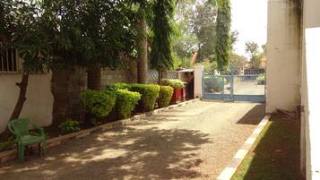 A gravel driveway leading to a gated entrance, surrounded by neatly trimmed hedges and trees.