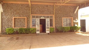 A building with a stone facade, a covered entrance, and a sign indicating a reception area. - Milimani Holiday Resort (Kisumu)