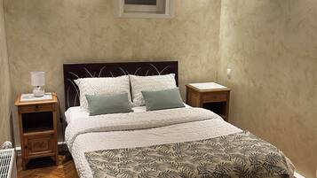Een slaapkamer met een groot bed, twee nachtkastjes, een radiator en een raam met zonwering.