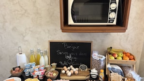 A breakfast buffet with various food items, a chalkboard sign, and a microwave. - La Ferme du Paradis (Merris)