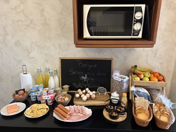 Un bufé de desayuno con diferentes alimentos, un letrero en una pizarra y un microondas.