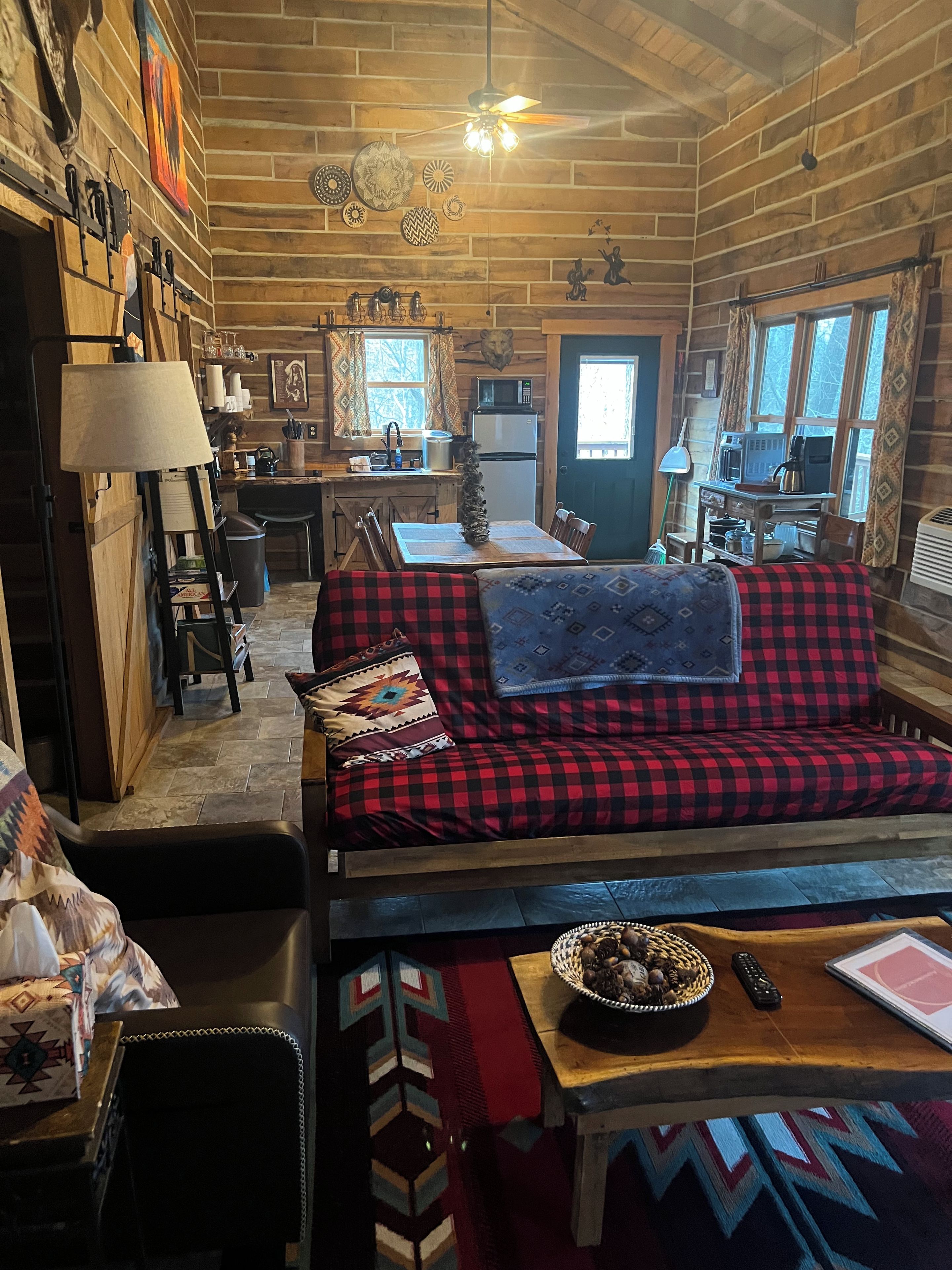 Un acogedor interior de cabaña con sofá, mesa de comedor y zona de cocina.